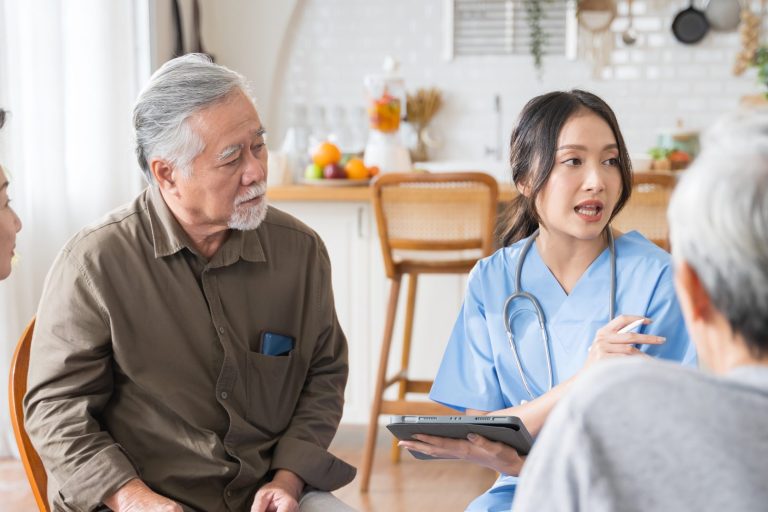 Group of Asian senior people sit in a circle in a nursing home and listen to nurse during a group elderly therapy session.