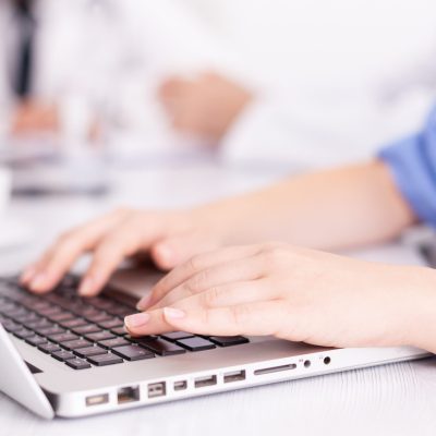 Close up of medical nurse typing on laptop during healtchare meeting with coworkers in hospital boardroom. Clinic expert therapist talking with colleagues about disease, medicine professional