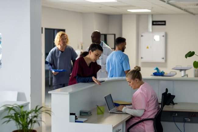 diverse-doctors-talking-at-reception-desk-at-hospi-2025-04-03-16-32-07-utc-min Aged care compliance tools | VCare Software