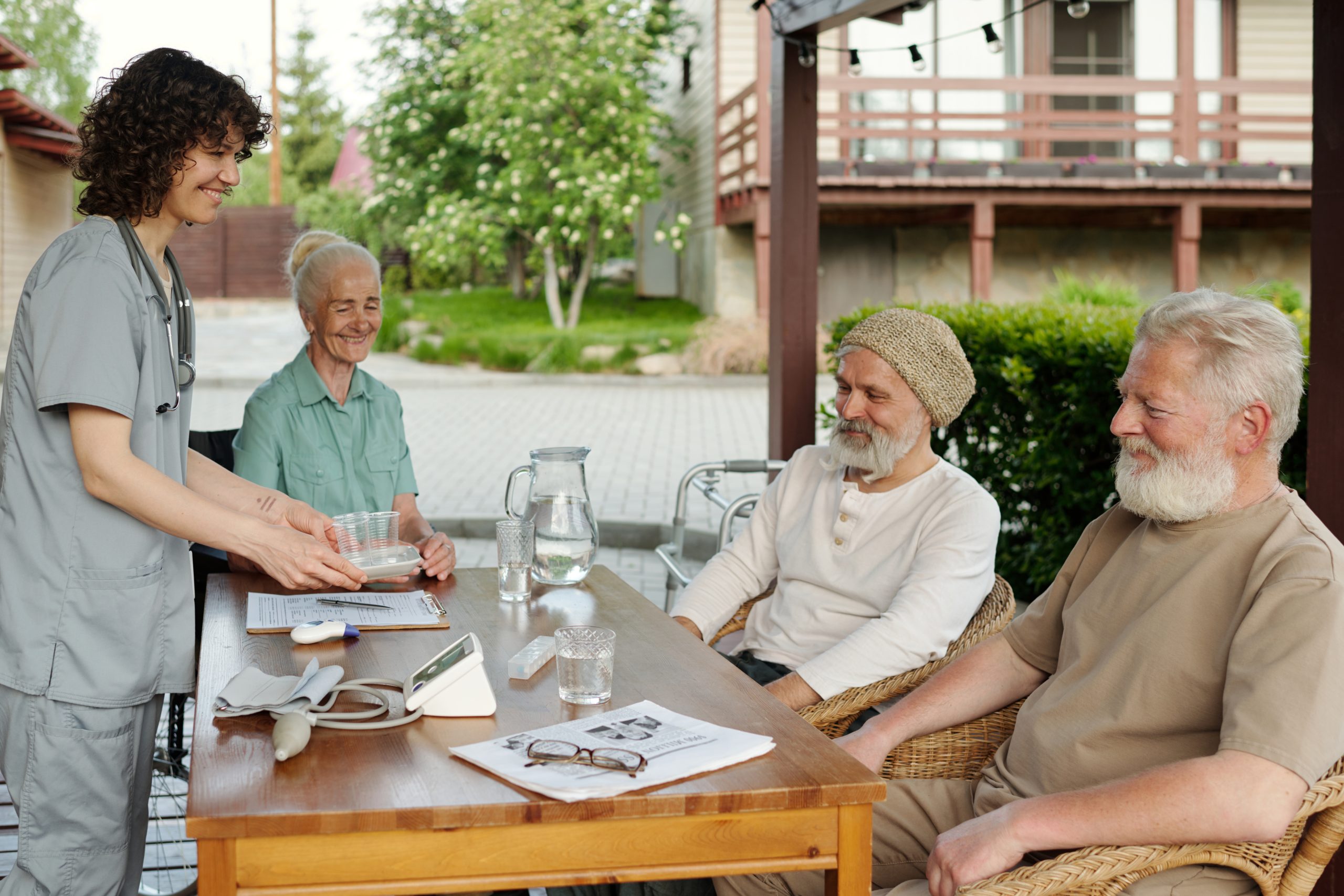 Happy young nurse bringing medicaments to group of senior people